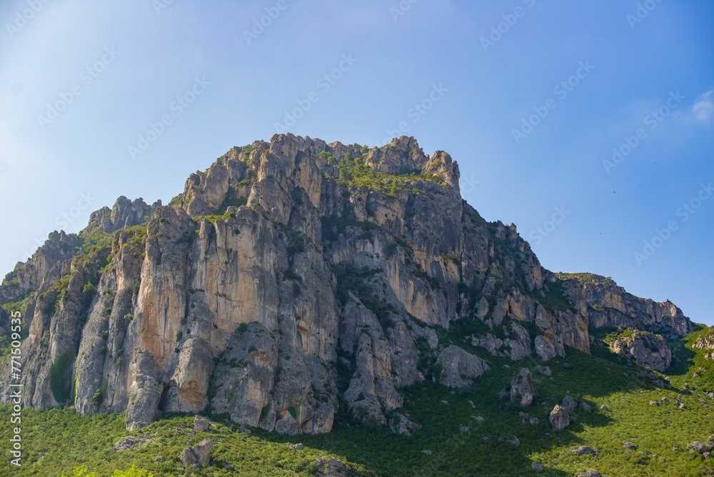 Stunning landscape featuring a rocky cliff overlooking lush green grass