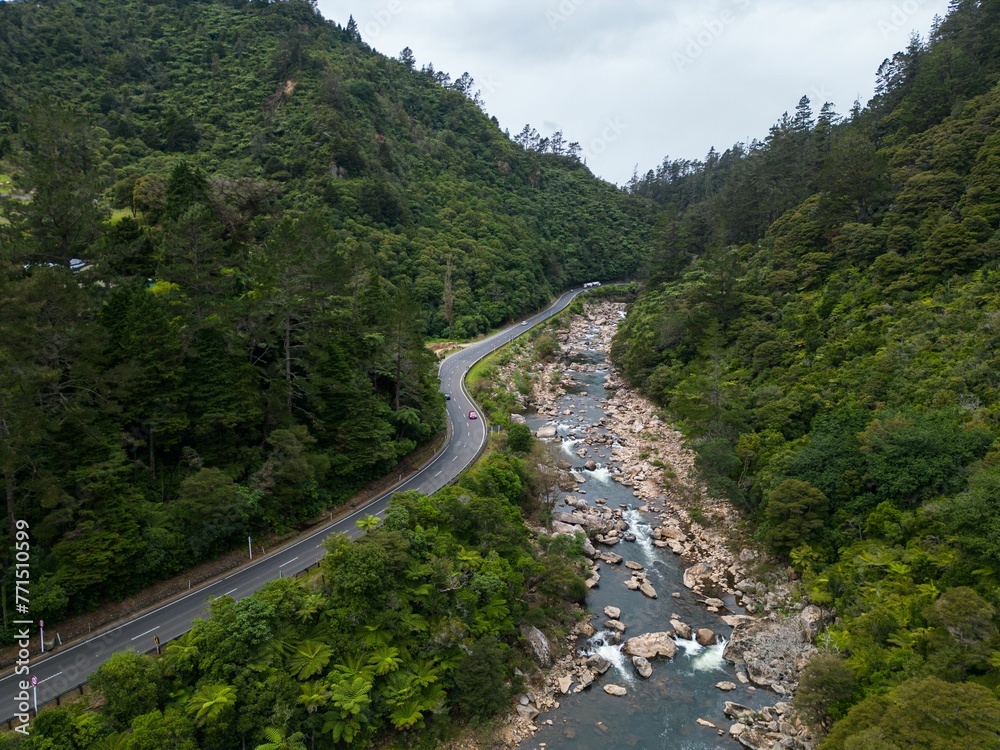Scenic view of a large river surrounded by lush green trees and a roadway in Karangahake Gorge Scenic view of a large river surrounded by lush green trees and a roadway in Karangahake Gorge