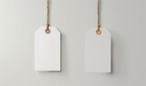 Two white rectangular cardboard price tags hang on string, blank and ready for labeling.
