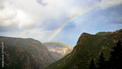 there is a rainbow over a mountain area with some trees