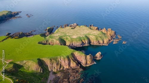 Aerial view of a small lush green island with rocky cliffs at the shore photo