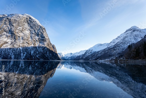 Stunning winter scene of a beautiful snow-capped mountain reflected in a lake in Olden, Norway