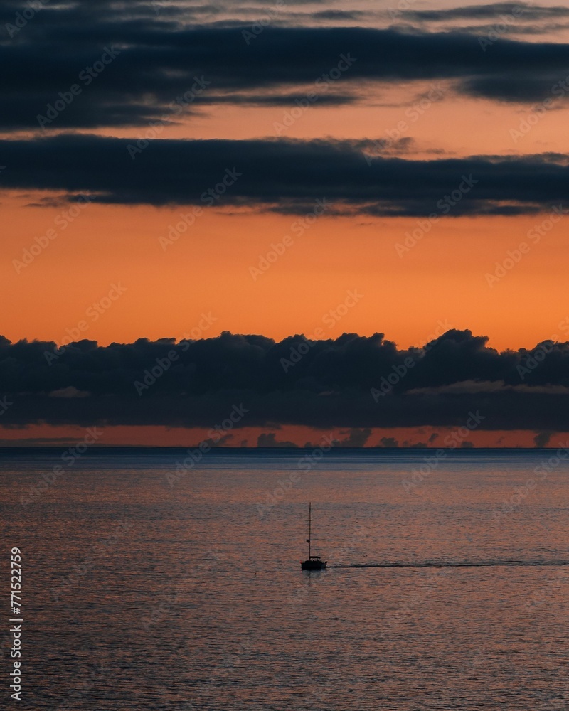 Small boat silhouetted against the sky at twilight, drifting on the vast expanse of a tranquil lake. Small boat silhouetted against the sky at twilight, drifting on the vast expanse of a tranquil lake.