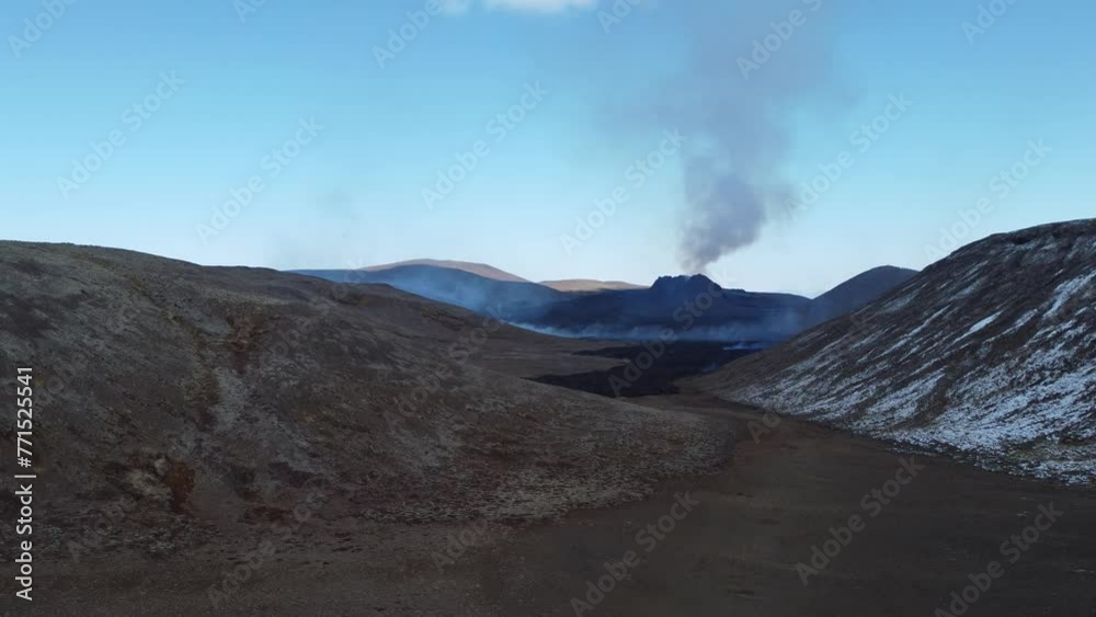 Drone view of mountains with a background of steam coming from a volcano Drone view of mountains with a background of steam coming from a volcano