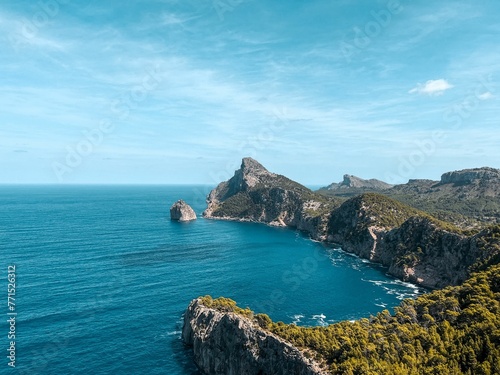 Stunning landscape of the coast featuring rocky cliffs and crystal blue ocean with a bright blue sky