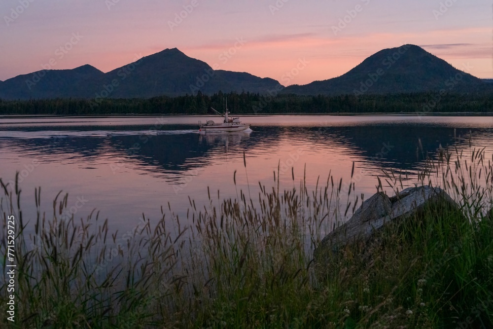 Small vessel is peacefully gliding across a tranquil lake in Alaska Small vessel is peacefully gliding across a tranquil lake in Alaska