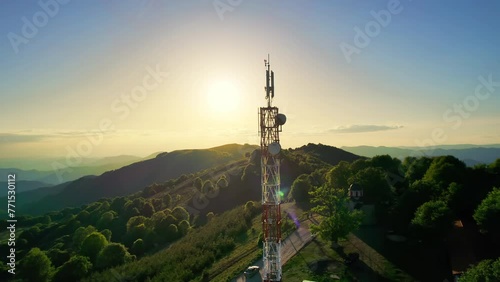 High telecommunication cell tower antenna at mountain high altitude nature on the background of beautiful orange sunset photo