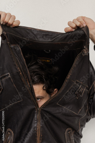 man takes off his leather jacket