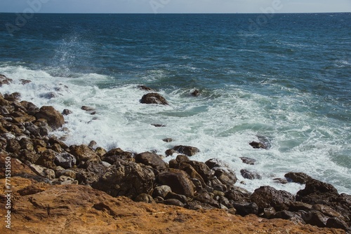 Rocky cliff overlooking an expansive ocean. © Wirestock