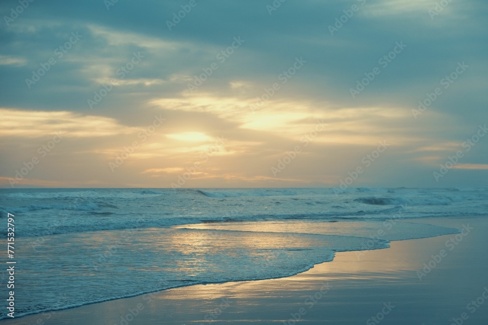 Fototapeta premium Beautiful sunset over the beach with the ocean waves gently crashing against the shore