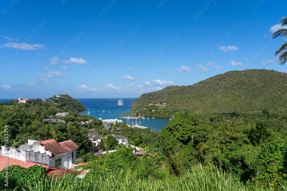 a view of a lush green hillside, mountains and a boat docked in the ocean