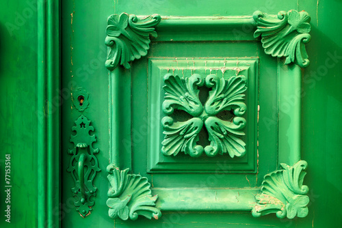 ornate detail of a wooden door painted in green