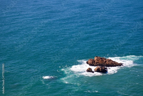 Aerial view of rock formations standing against a vast, peaceful expanse of ocean water