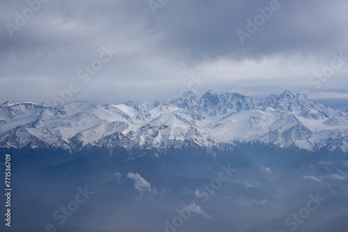 Aerial view of the snow-capped Ten-Zan Bodga peak with clouds floating above it © Wirestock