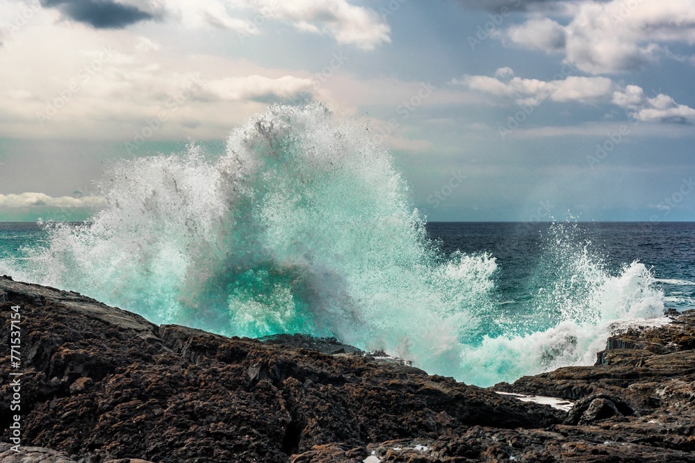 Scene of the Hawaii ocean with a wave of water crashing over rocks