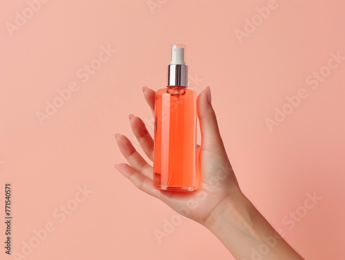 A young woman's hand is holding a beautiful unlabeled cosmetic bottle on a plain color background. 