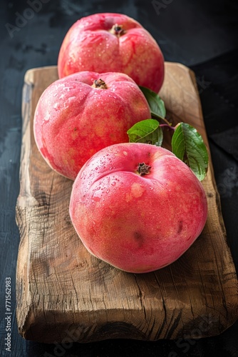 Three ripe peaches placed on a wooden cutting board