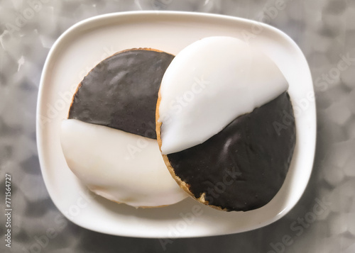Two black and white cookies on a plate photographed from above