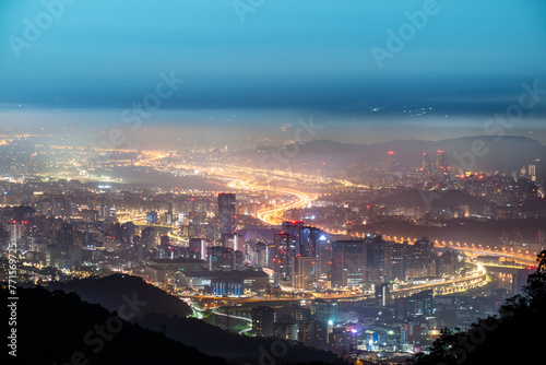 A layer of white clouds and mist over Taipei City, together with the city lights, form a colorful glazed light.
