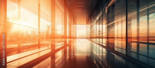 Amber tints and shades of orange fill the office floor as sunlight pours through the glass windows, reflecting off the wood flooring and creating a warm heat within the symmetrical space