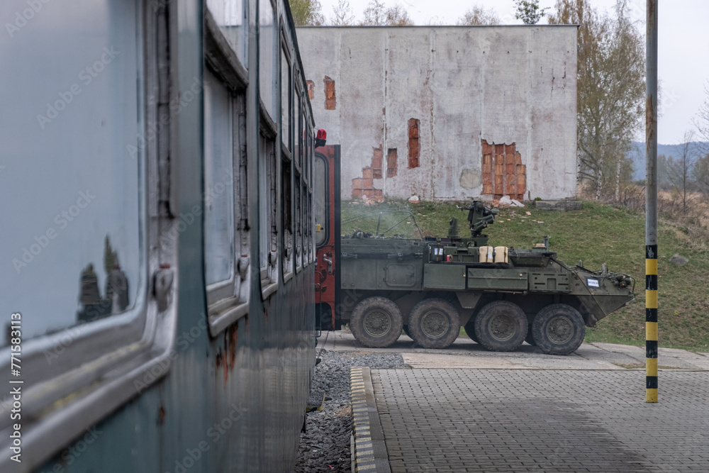 A military vehicle is parked in front of a train