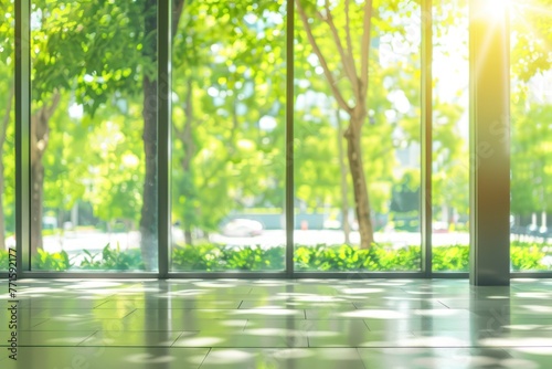 Blurred empty modern open space office with large windows and green trees on the outside