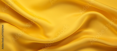 A close up of a bright yellow satin fabric resembling waves, like the petals of a rose family flower. The intricate pattern looks like art on silk, creating a liquidlike effect