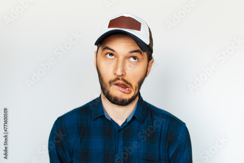 Studio portrait of young man makes funny face, weird expression, on background of white.