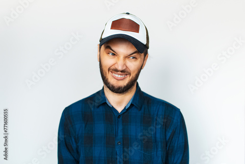 Studio portrait of young man makes funny face, weird expression, on background of white.
