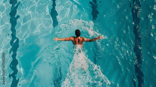 A man is swimming in a pool of water, moving his arms and legs to propel himself through the clear blue liquid