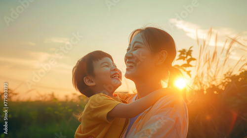Asian mother and son smiling at sunset, woman holding child in her arms, nature background, warm colors