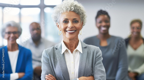 Empowerment of Older Adults. A confident senior black businesswoman leading a corporate meeting, standing at the forefront with diverse team members listening intently. Leadership and Expertise. © Katerina Bond
