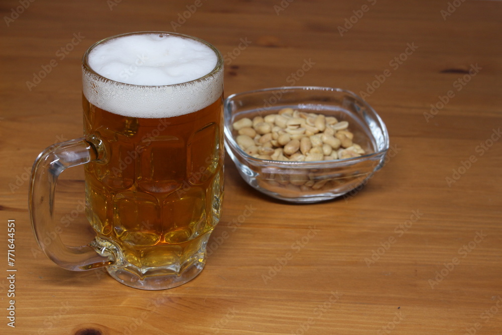 Image of a glass of beer and a plate of nuts. Image of a glass of beer and a plate of nuts.
