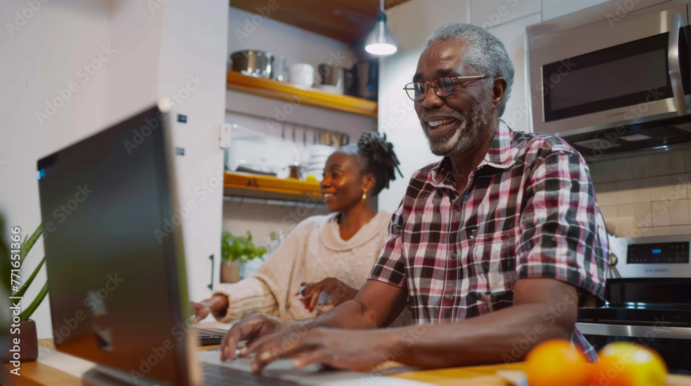 Two joyful seniors share a moment looking at a laptop in a kitchen setting. Two joyful seniors share a moment looking at a laptop in a kitchen setting.
