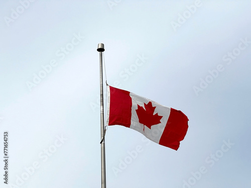 Flag of Canada flying against a blue sky.