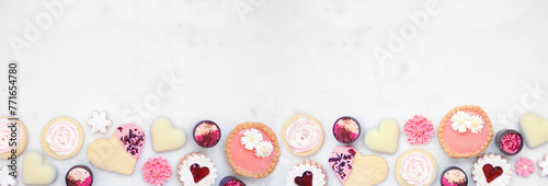 Mothers Day or love themed baking bottom border with a selection of cookies and sweet treats. Top down view on a white marble banner background with copy space. photo