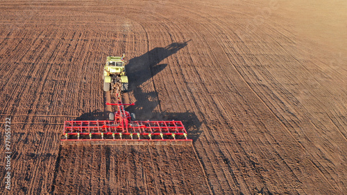 Panoramic aerial view of a tractor with a trailed combined machine performing seedbed preparation in the field. photo