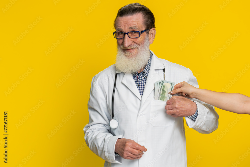 Senior speaker doctor cardiologist man receiving bribe from patient taking money from client hiding cash into pocket. Illegal corruption in medicine. Sneaky apothecary grandfather on yellow background Senior speaker doctor cardiologist man receiving bribe from patient taking money from client hiding cash into pocket. Illegal corruption in medicine. Sneaky apothecary grandfather on yellow background