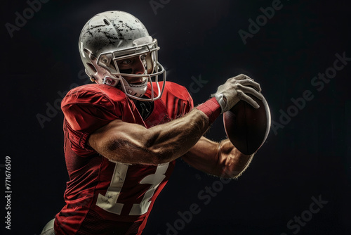 An American football player striking a pose with a ball against a black background