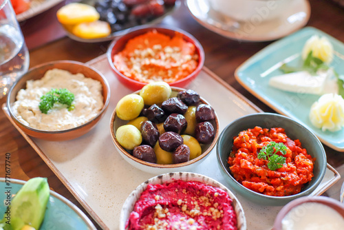 Delicious rich Traditional Turkish breakfast include tomatoes, cucumbers, cheese, butter, eggs, honey, bread, bagels, olives and tea cups.