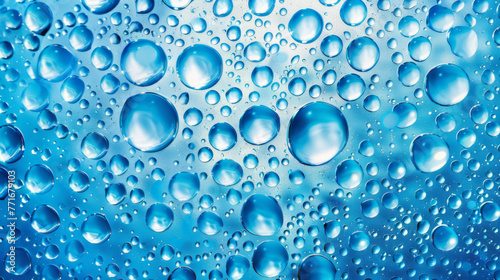 Condensed water droplets of varying sizes create a pattern on a bright blue background.