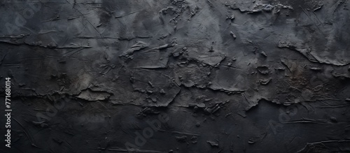 A close up of a weathered black wall with flaking paint resembling a bedrock outcrop in a natural landscape, contrasted with grey wood and freezing rock