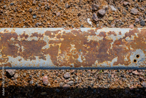 A metal rusty pole lies on the ground