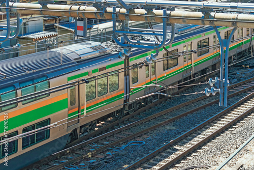 Industrial or mass transit background featuring detail of electrical railroad with local suburban train, rails and contact lines illustrating modern urban public transport concept, Tokyo, Japan.