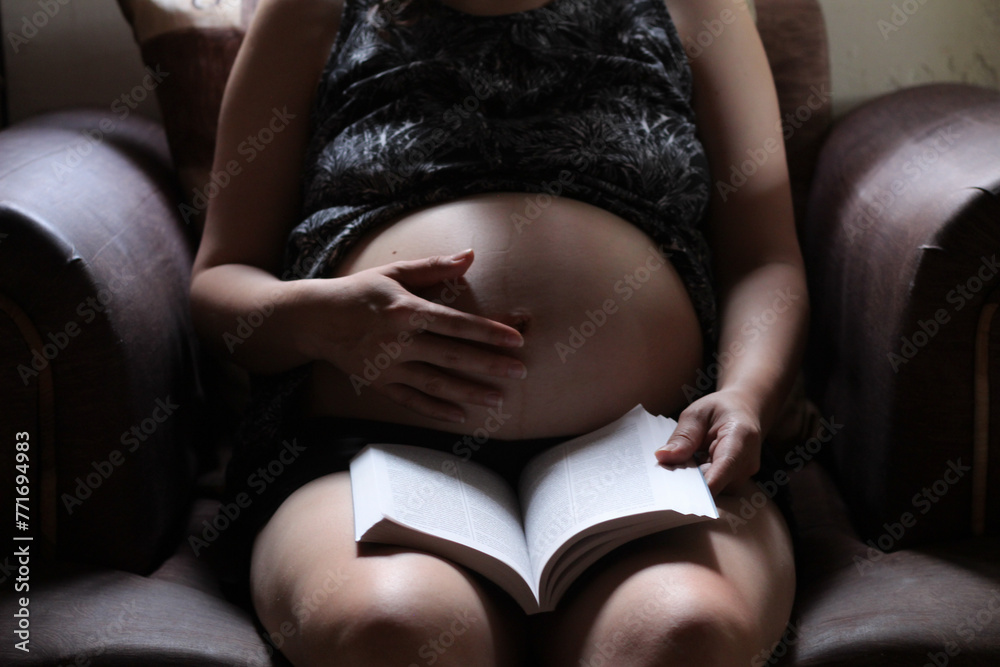 mujer embarazada leyendo. - obrazy, fototapety, plakaty 