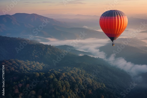 Colorful hot air balloon flying over misty mountains at sunrise, beautiful landscape background. Concept of travel and adventure with copy space. 