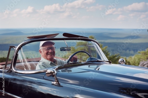 An elderly man smiles while driving a vintage convertible car on a sunny day