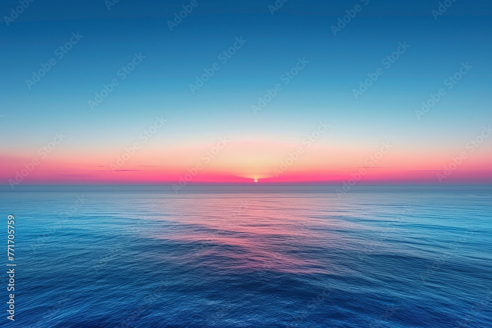 Beautiful blue ocean with a pink and orange sunset in the background. The sky is clear and the sun is setting, creating a serene and peaceful atmosphere