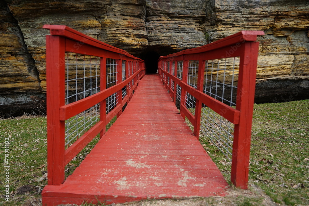 A red man-made bridge leads into a rock tunnel at Pier County Park in Rockbridge, Wisconsin a Native American historical site. A red man-made bridge leads into a rock tunnel at Pier County Park in Rockbridge, Wisconsin a Native American historical site.