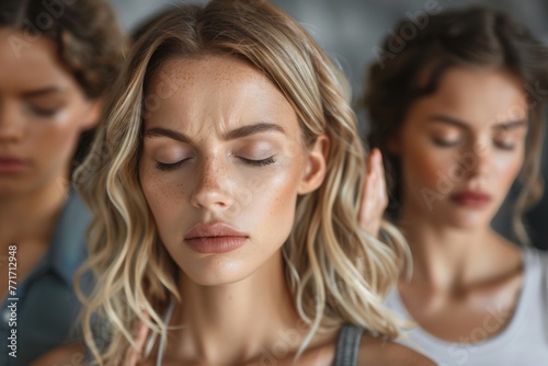 Woman with closed eyes centering the frame, flanked by out-of-focus figures, conveying thoughtfulness